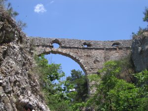 A view of Kemerdere aqueduct before the restoration, stones are grey and the arch is unstable, with stones fallen in many of the smaller arches.